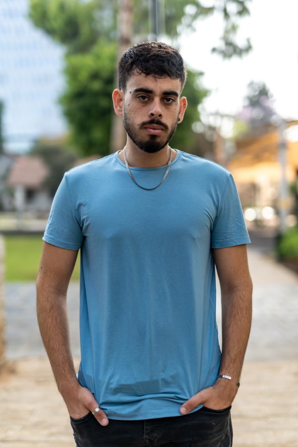 a man in a blue shirt standing on a sidewalk